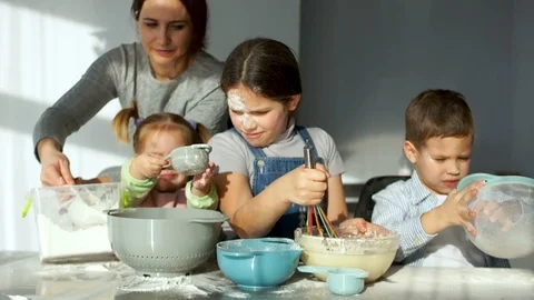 Clutter in the kitchen. Three cheerful children knead the dough for pies. Mom Stock Footage 86940255