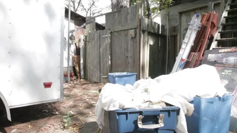 Cluttered Backyard with Storage Bins, Trailer, and Wooden Fence Stock-Footage 345278912