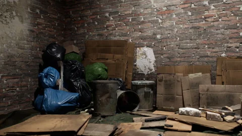 Cluttered interior space with cardboard boxes and trash bags in a dim room 動画素材 321352320