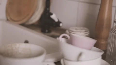 Cluttered kitchen table with dirty dishes near white sink and black faucet,.. Stock Footage 334334391