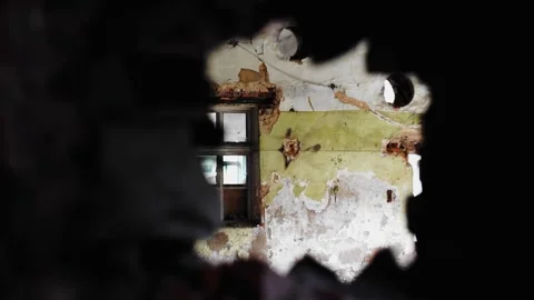 A cluttered room can be seen through a hole in the wall of an old house Stock Footage 304997094