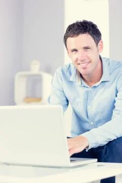 Cmiling casual man looking at camera using laptop 스톡 사진