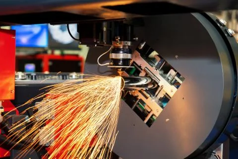 CNC laser cutting metal pipe with bright sparkle in factory. Industry machine Stock Photos