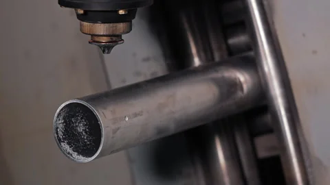 CNC laser head aligned with metal tube, high-precision cutting setup, Industrial Stock Footage 311074919