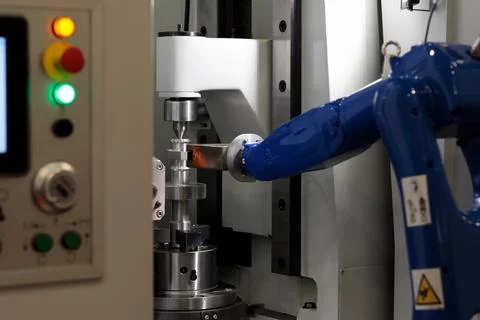 CNC machine and robotic arm loading workpieces Stock Photos