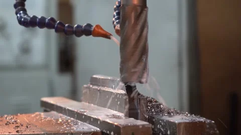 CNC machine drilling metal block with coolant spray Stock Footage 323301023