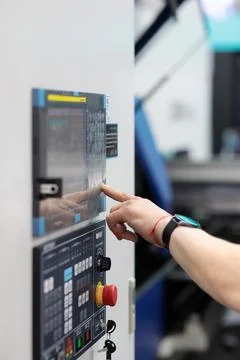 CNC machine operator working at the control panel Stock Photos