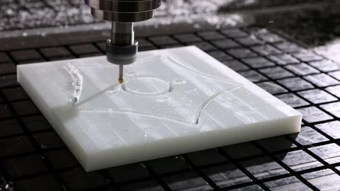 A CNC machine is precisely carving a complex pattern into a white block Stock Footage 314984924