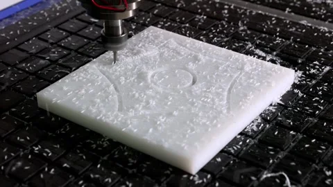 A CNC router machine working on a white plastic block, engraving a pattern .. Stock Footage 318001506