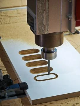 CNC router spindle cutting slots on a white wood panel in workshop Stock Photos
