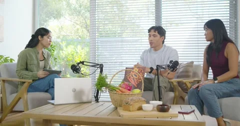 Co-hosts and guest discussing on studio set, center male holding yellow fruit as Stock Footage 335212495