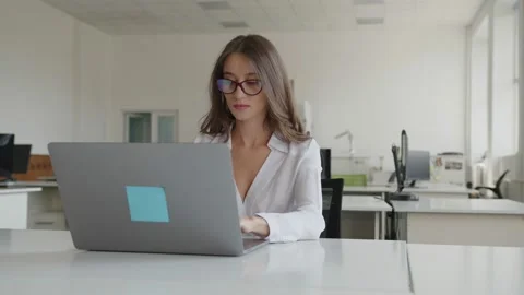 Co-worker sits and typing on her grey laptop Vidéo 157968496