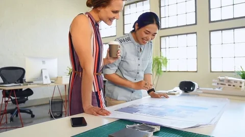 Co-workers with floor plans layouts in architecture firm Stock Footage 73312874