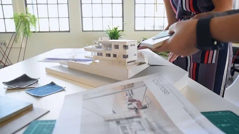 Co-workers with floor plans layouts in architecture firm Stock Footage 73312937