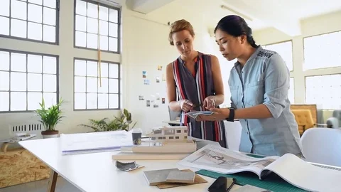 Co-workers with floor plans layouts in architecture firm Video stock 73312942