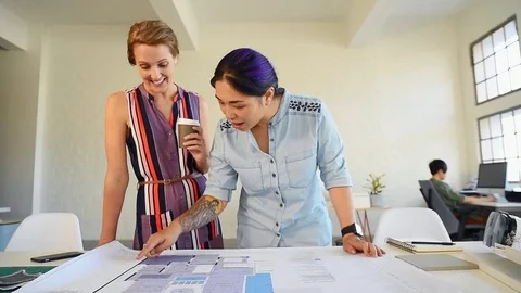 Co-workers with floor plans layouts in architecture firm Video stock 73312964