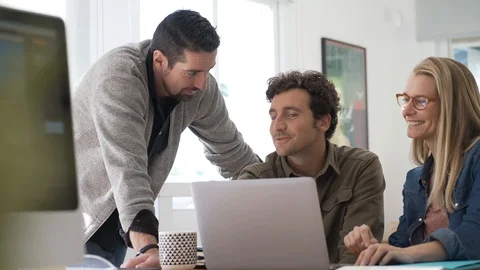 Co-workers gathering in office and using laptop Stock Footage 121457014