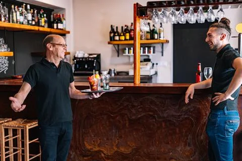 Co-workers serving drinks to their customers. Co-workers talking in their small Stock Photos
