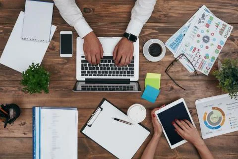 Co-workers sharing the same desk with customized workspace and working with a Stock Photos