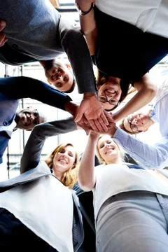 Co-workers standing in circle looking down Stock Photos