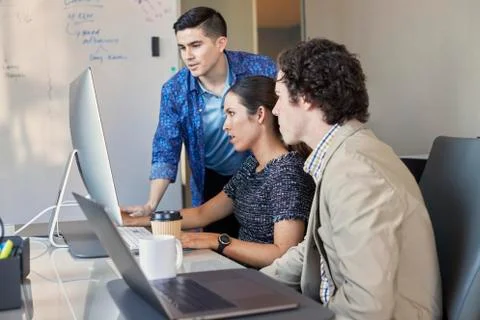 Co-Workers talking at computer in office, dry erase board with flowchart in Foto stock