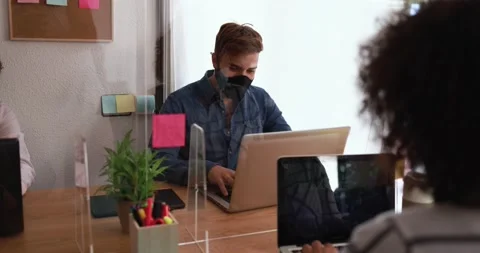 Co-workers using laptops behind safety glass Stock Footage 141050354