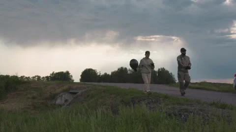 Co workers walking with device and paraglider under cloudy sky Stock Footage 317195144