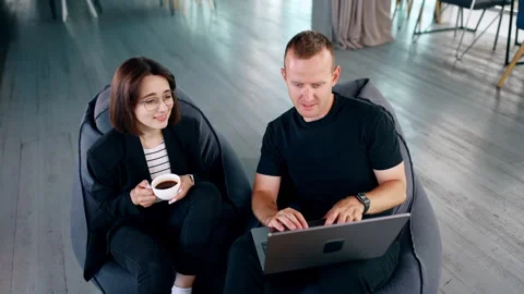 Co-working people sit in soft bean bag chairs. Stock Footage 277938619