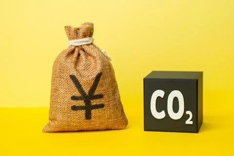 A CO2 cube and a yen or yuan money bag. Waste recycling and profit generati.. Stock Photos