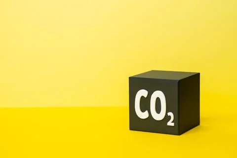 A CO2 cube on a yellow background. Emissions and environmental pollution. C.. Stock Photos