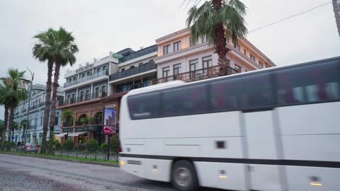 Coach bus moving through historic European city street with palm trees 스톡 동영상 341852011