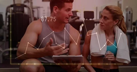 Coach checking clipboard and explaining fitness progress while animated graph Stockbeeldmateriaal 323386090