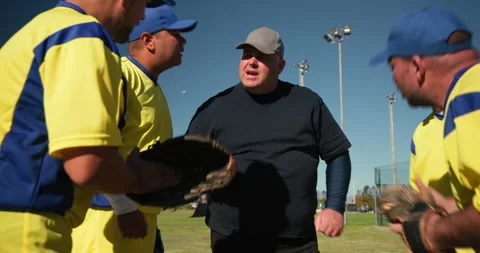 Coach with diverse baseball players speaking in huddle on field, slapping gloves Stock Footage 340964135