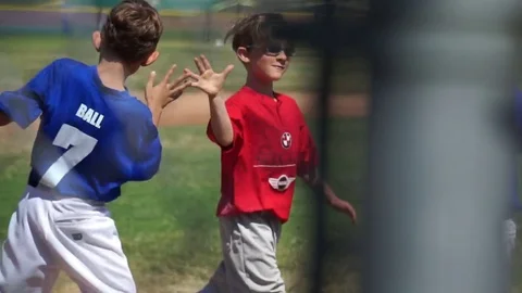 The coach gives a high-five to a boy playing little league baseball. Stock Footage 70435544
