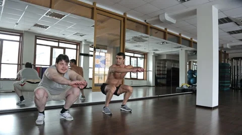 Coach in the gym watching the beginner doing squats Stock Footage 64093769