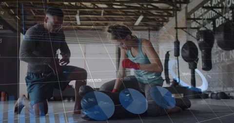Coach kneeling checking timer, trainee striking bag, HUD showing metrics Stock Footage 323372651