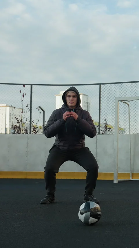 Coach Performing Squats with Soccer Ball on Urban Sports Ground Stock Footage 316633366