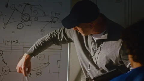 Coach Presenting Game Plan on Whiteboard to Young Athlete Team Stock Footage 339016649