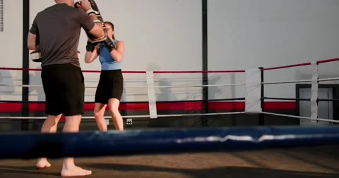Coach tapping pads, trainee wearing boxing gloves throwing jab and cross in Stock Footage 341942738
