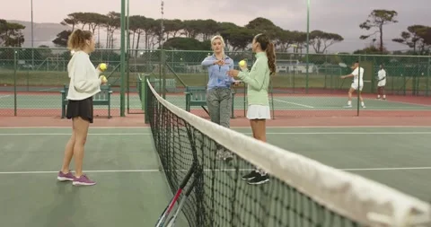 Coach tapping watch, using tablet guiding female trainees tossing yellow balls Stock Footage 342232808