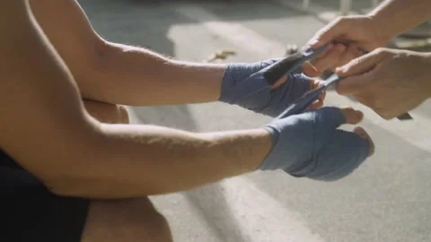Coach trainer taking off hand elastic straps from boxer's hands after training Stock-Footage 131278560