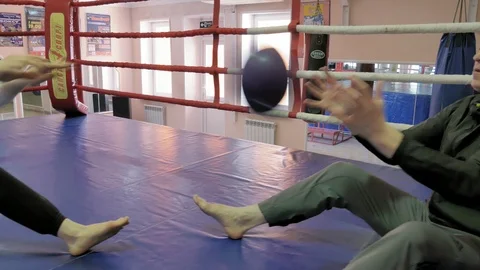 The coach in training throws a heavy ball with a female kickboxer in the ring Video stock 90237291