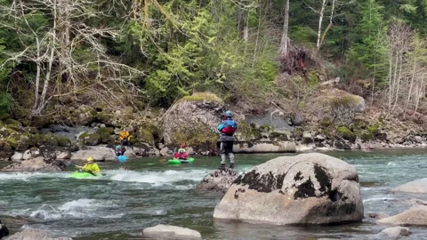 The coach watches the training of the kayak team on the mountain river. Kayaking Stock Footage 244106907