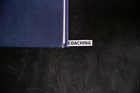 Coaching Concept with Text Partially Covered by Book on Black Grunge Surface Stock Photos