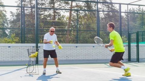 Coaching or teaching play tennis on a court outdoor. Training of professional Stock Footage 68941263