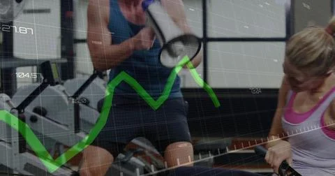 Coaching trainer in blue top, trainee in white tank rowing at gym, megaphone, 스톡 사진
