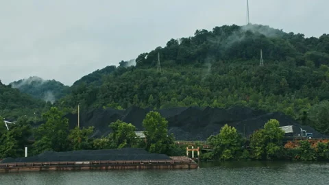 Coal barge navigating a river through misty mountains Video stock 334101207