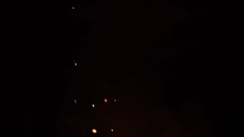 Coal embers scattering in wind with trailing smoke over black background Stock Footage 337175458
