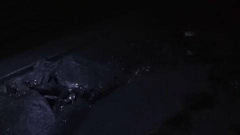 Coal mining in a coal mine. Rays of the mine lamp slide on the coal Stock Footage 83257695