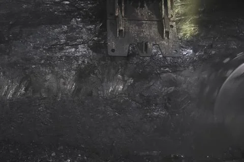 Coal mining in mine, a rotating disc scraping coal from the seam. Stock Photos